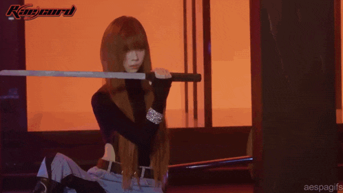a woman holding a sword and a microphone in front of a sign that says ray card