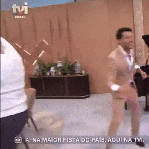 a man in a tan suit is dancing on a tv show