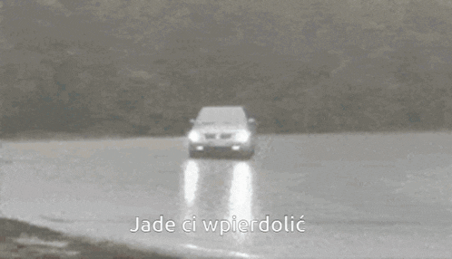 a silver car is driving on a wet road with the words jade ci wpierdolic written on the bottom .