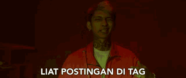 a man in a red jacket with the words liat postingan di tag below him