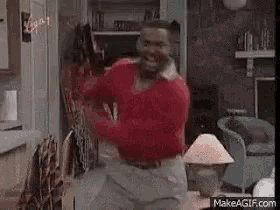 a man in a red sweater is standing in a living room .