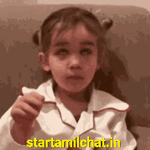 a little girl is holding something in her hand and the website starttamilchat.in is in the corner