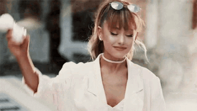 ariana grande is wearing sunglasses and a choker while holding a cotton candy in her hand .