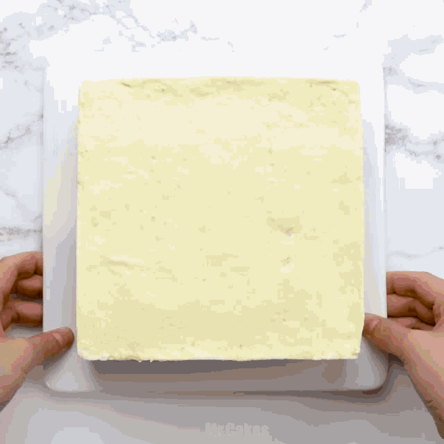 a person is holding a white plate with a piece of cheese on it that says mr.cakes