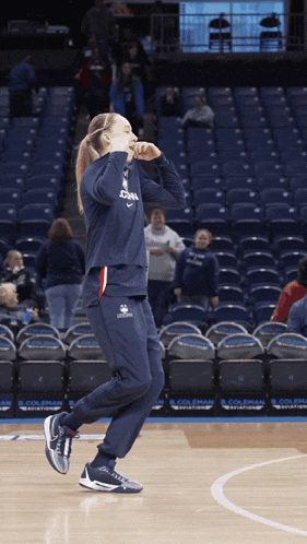 a female basketball player stands on a court in front of an empty stadium that says coleman on the sidelines