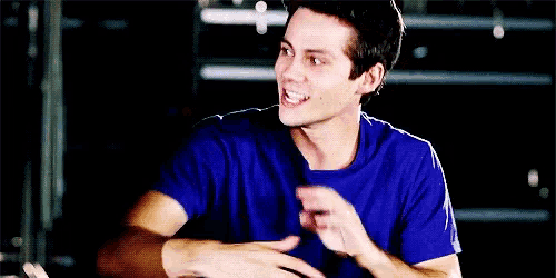a young man in a blue shirt is laughing with his mouth wide open