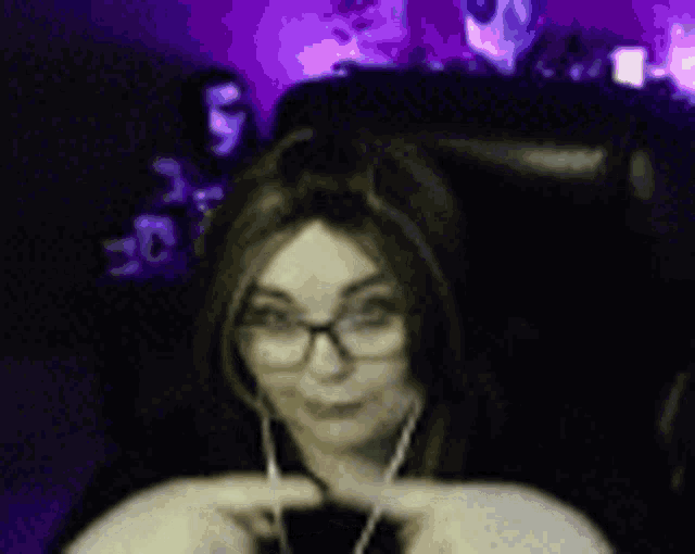 a woman wearing glasses and headphones is sitting in a chair in front of a computer screen .