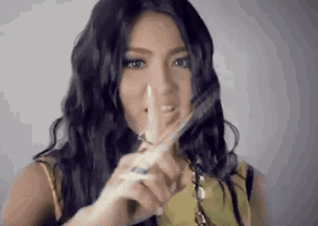 a woman is holding a pair of scissors in front of her face and making a shhh gesture .