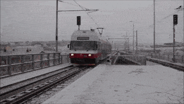 a red and white train is on the tracks with a sign that says ' stop ' on it