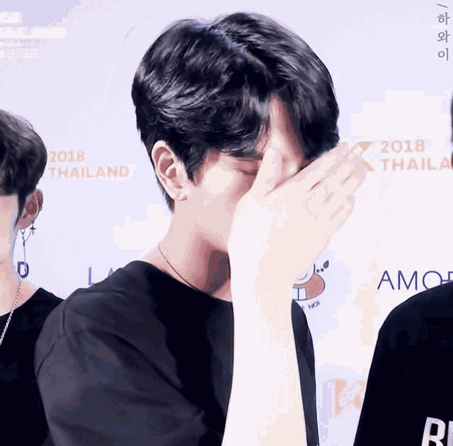 a man covering his face in front of a 2018 thailand sign