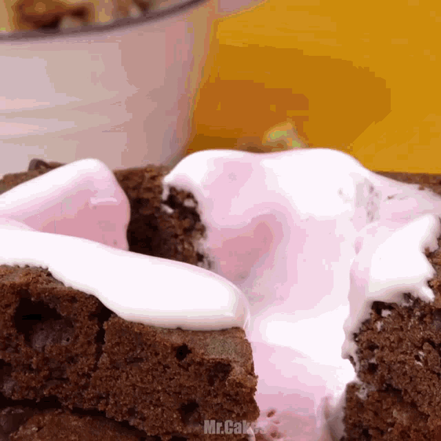 a close up of a brownie with pink and white frosting and the words mr.cake below it