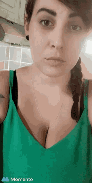 a woman in a green tank top has a momento icon on the bottom left