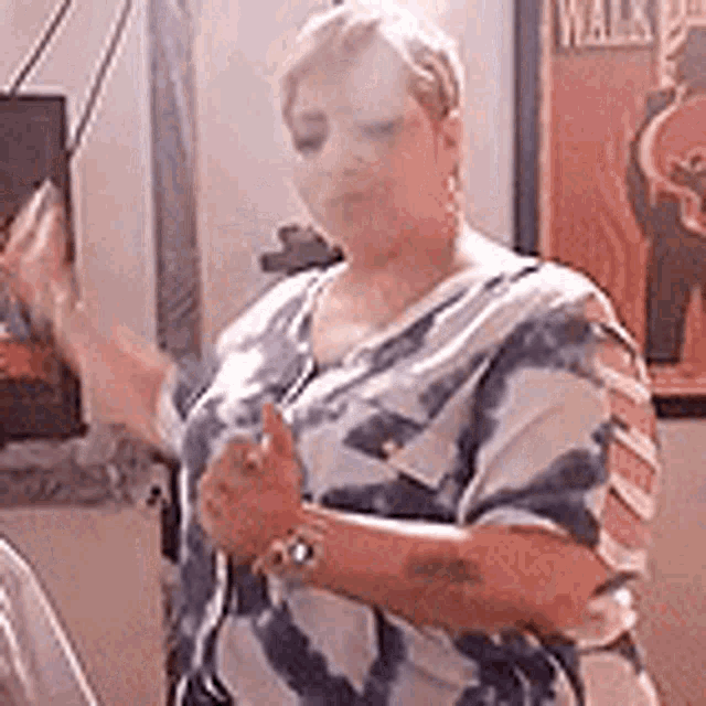 a woman in a tie dye shirt is giving a thumbs up in front of a poster .