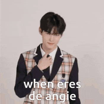 a young man in a suit and tie is adjusting his tie and says `` when eres de angie '' .