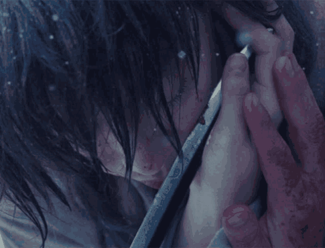 a close up of a person holding a sword with blood on their hands