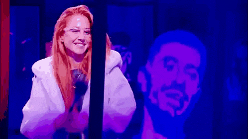 a woman is smiling in front of a man 's shadow in a dark room