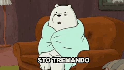 ice bear is wrapped in a blanket and sitting on a couch .