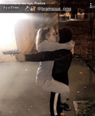 a man is holding a woman in his arms while holding a gun in his hand