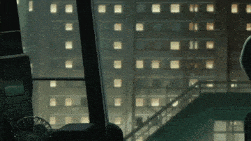 a fan sits on a table in front of a window looking out to a city at night