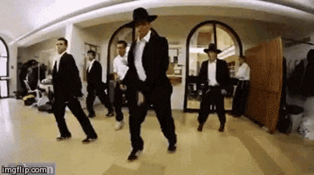 a group of men in suits are dancing together in a room .