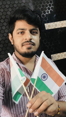 a man in a striped shirt is holding two small flags in his hands
