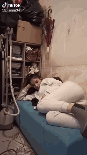 a woman is laying on a blue couch with a cell phone in her hand