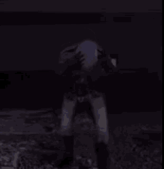 a person is standing in the dark with their hands on their hips .