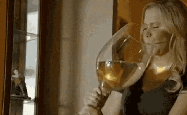a woman is drinking a glass of wine from a large glass .