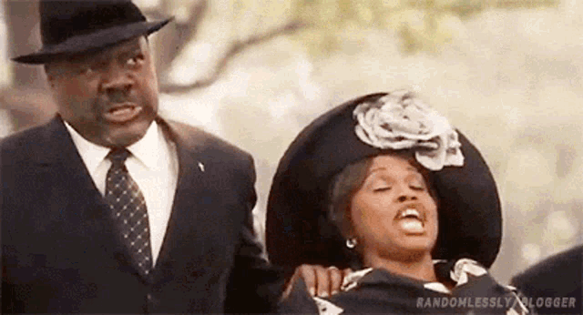 a man in a suit and tie is standing next to a woman in a funeral dress .