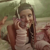 a woman is laying on a bed talking on a telephone while smiling .