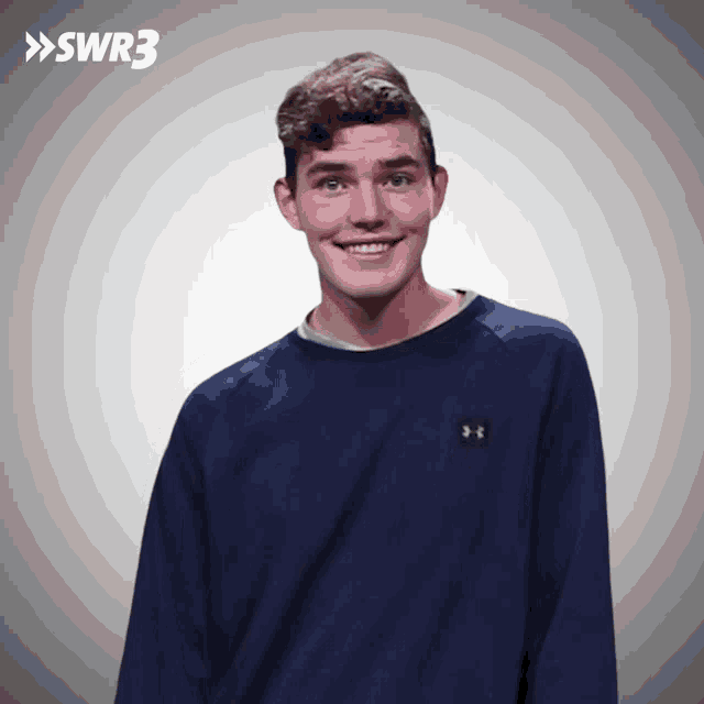 a man in a blue under armour sweatshirt smiles