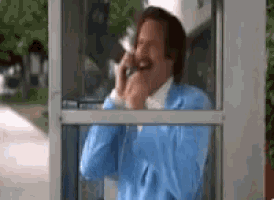 a man in a blue jacket is laughing while talking on a phone