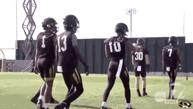 a group of football players are standing on a field and one has the number 30 on his back .