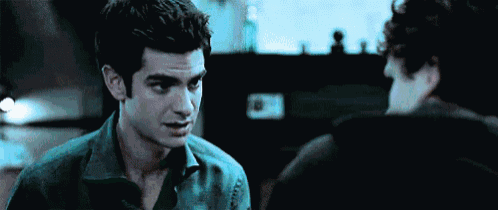 two men are standing next to each other in a dark room and talking to each other