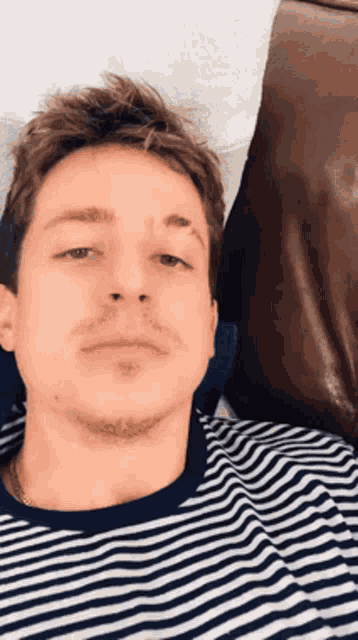 a man wearing a striped shirt is laying on a bed