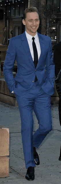 a man in a blue suit and black tie smiles