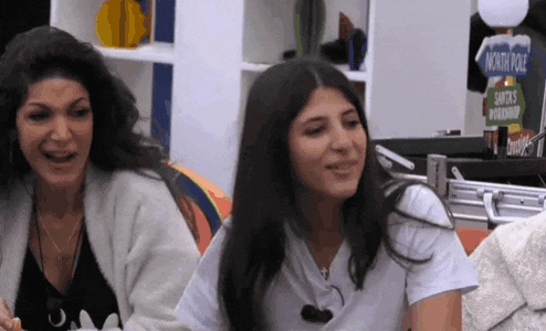 two women are sitting in front of a sign that says ' santa 's workshop '