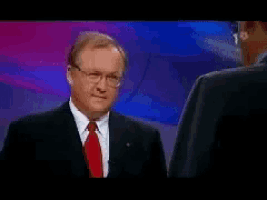a man in a suit and tie is talking to another man in a suit