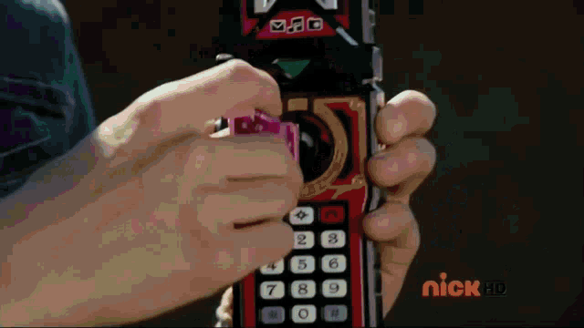a person is holding a remote control with the nick hd logo on the bottom right