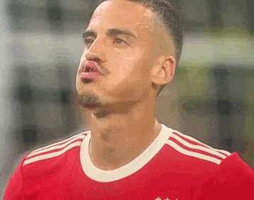 a soccer player is making a funny face while wearing a red and white jersey .