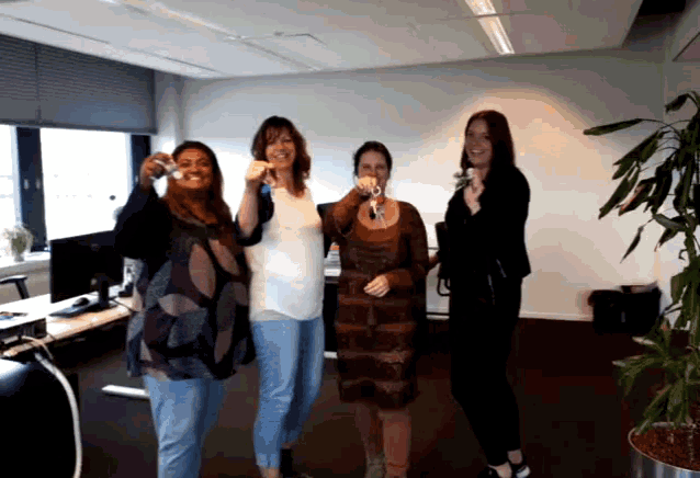 a group of women are standing in a room holding up keys