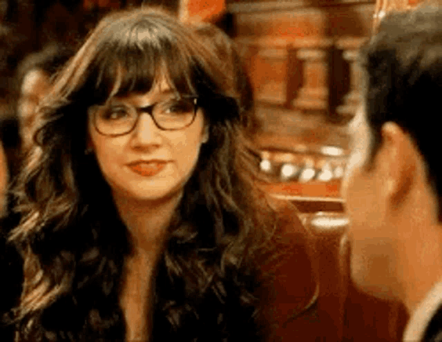 a woman wearing glasses is talking to a man in a bar .