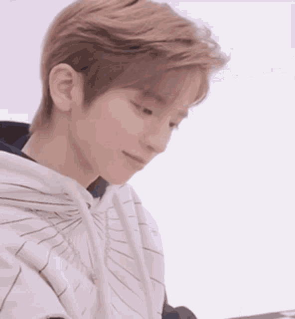 a close up of a young man wearing a hoodie and looking down .
