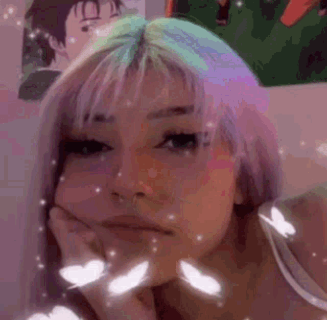 a girl with purple hair is making a face with her hand on her chin .