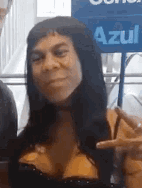 a woman with long black hair is making a funny face and giving a peace sign .