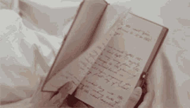 a person is holding a book with a handwritten letter in it