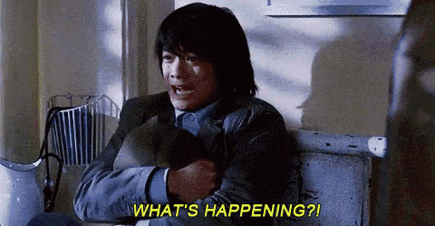 a man is sitting at a table holding a pillow and asking what 's happening ?