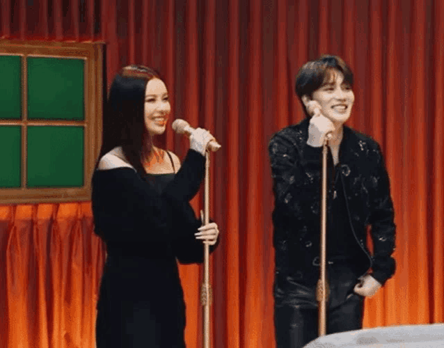 a man and a woman singing into microphones on a stage .