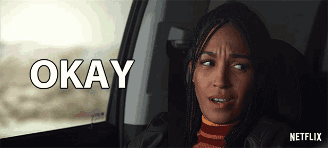 a woman is sitting in a car with the word okay on the screen