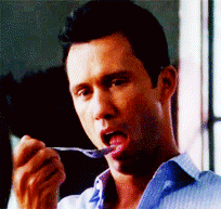 a man in a blue shirt is holding a spoon in his mouth